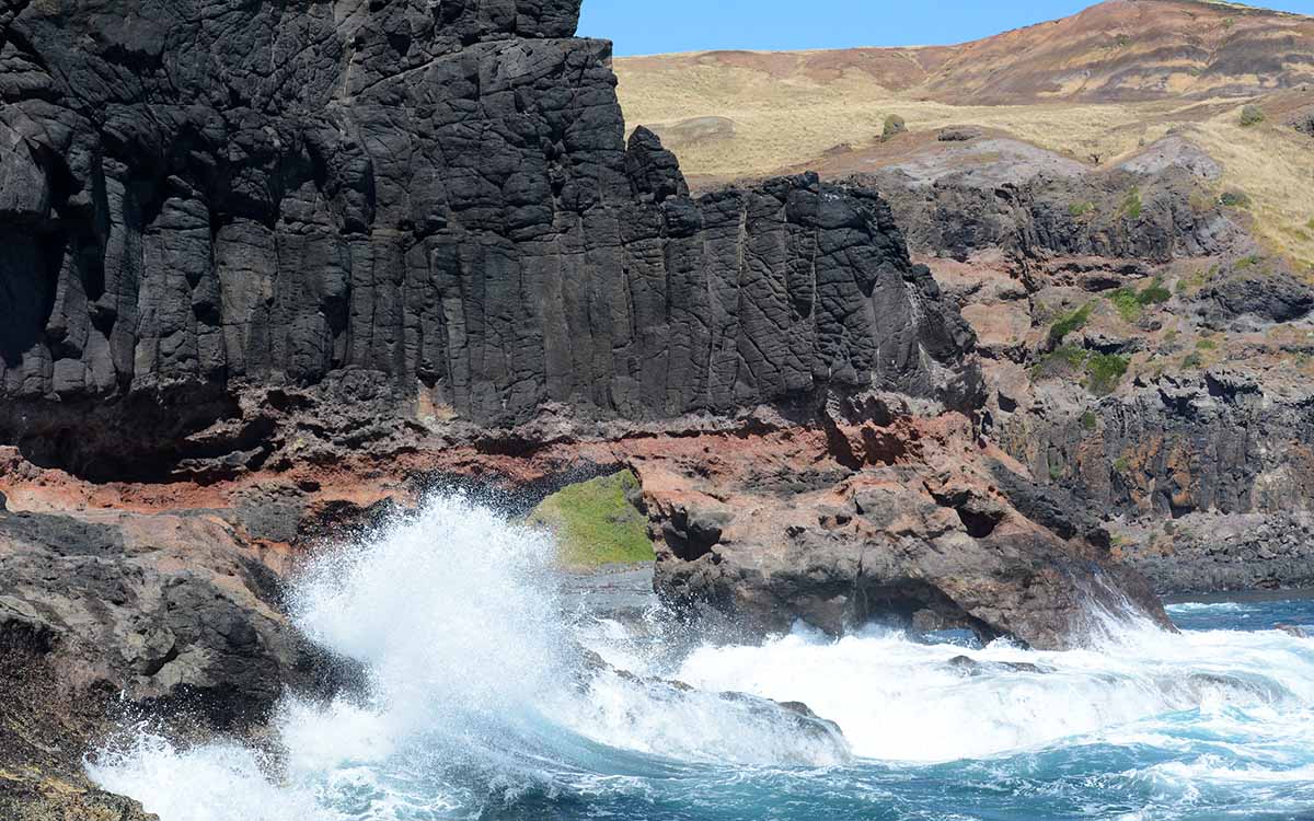 Waves crashing against a coastal archway rock formation at Bushrangers Bay